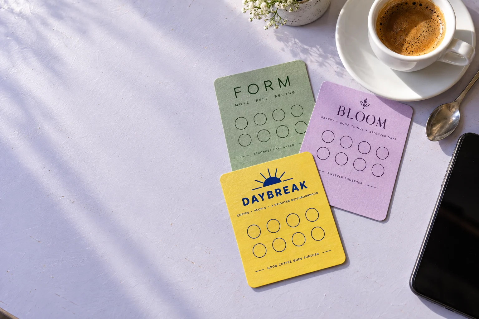 Original Daybreak, Form, and Bloom loyalty card illustrations beside a coffee and phone.